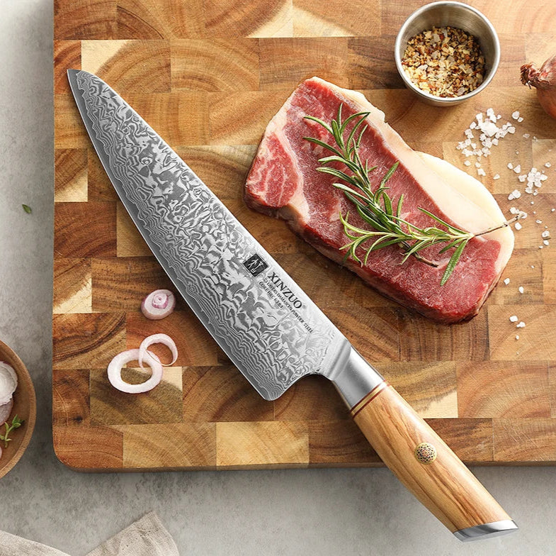 Notre couteau de chef en acier Damas c'est une lame ultra tranchante aux motifs uniques et une somptueuse poignée en bois noble d'olivier orné d'une fleure en cuivre pour sublimer le couteau