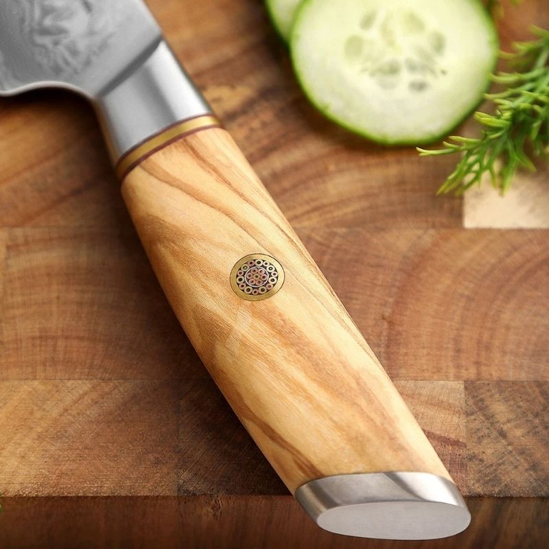 Notre couteau de table en acier Damas est muni d'une somptueuse poignée en bois d'olivier noble et chaleureux dans laquelle une petite fleur en cuivre est subtilement incrustée pour affirmer son caractère luxueux et rehausser son raffinement artisanal